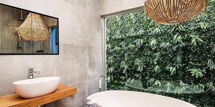 Image of a Pietra Bianca bath in a bathroom setting with a glass wall overlooking an outside garden hedge